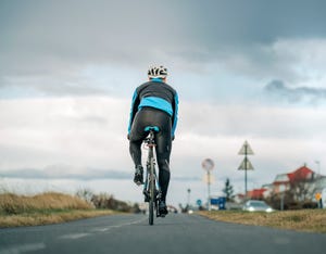 cyclist riding his bike on empty road, does cycling build glutes