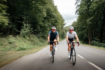 cyclists riding bikes on the road through the forest