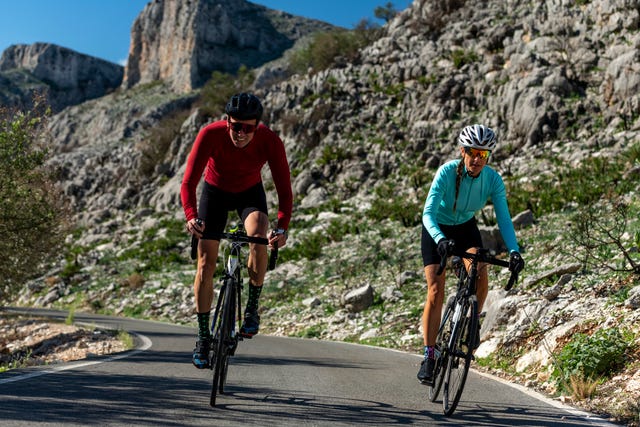 cyclists together riding bicycles on road in front of rocks