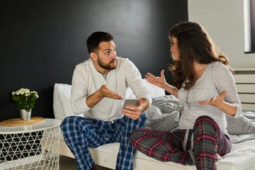 dissatisfied young brunette arguing with boyfriend over smart phone