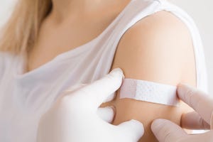 doctor in white rubber protective gloves putting an adhesive bandage on young woman's arm after scratch on skin or injection of vaccine first aid medical, pharmacy and healthcare concept