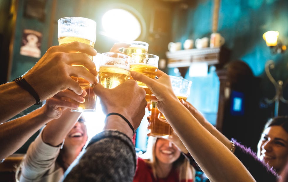 group of happy friends drinking and toasting beer at brewery bar restaurant friendship concept with young people having fun together at cool vintage pub focus on middle pint glass high iso image