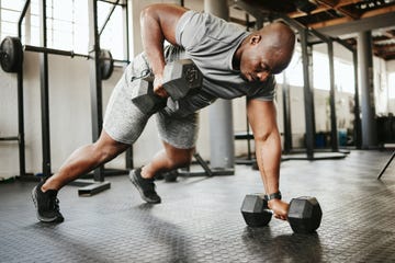 dumbbell, fitness and bodybuilder black man with workout training in gym or garage studio for wellness, body goal and motivation power, strong and african sports man doing push up exercise with gear