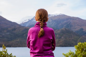 a red haired girl with a french braid looking at mountains