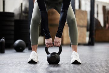 shot of a womans legs as she lifts a kettlebell