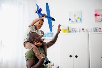 happy little multiracial boy with his father playing together indoors in childrens room