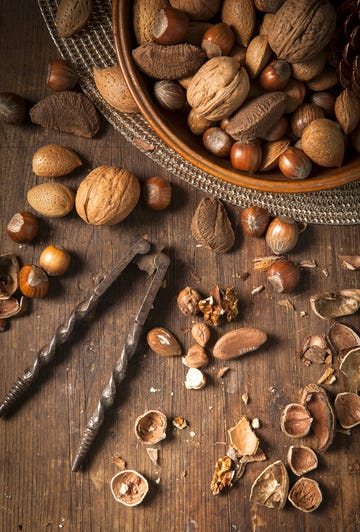 Festive bowl of mixed whole nuts in shells in a wooden bowl on a gold placemat