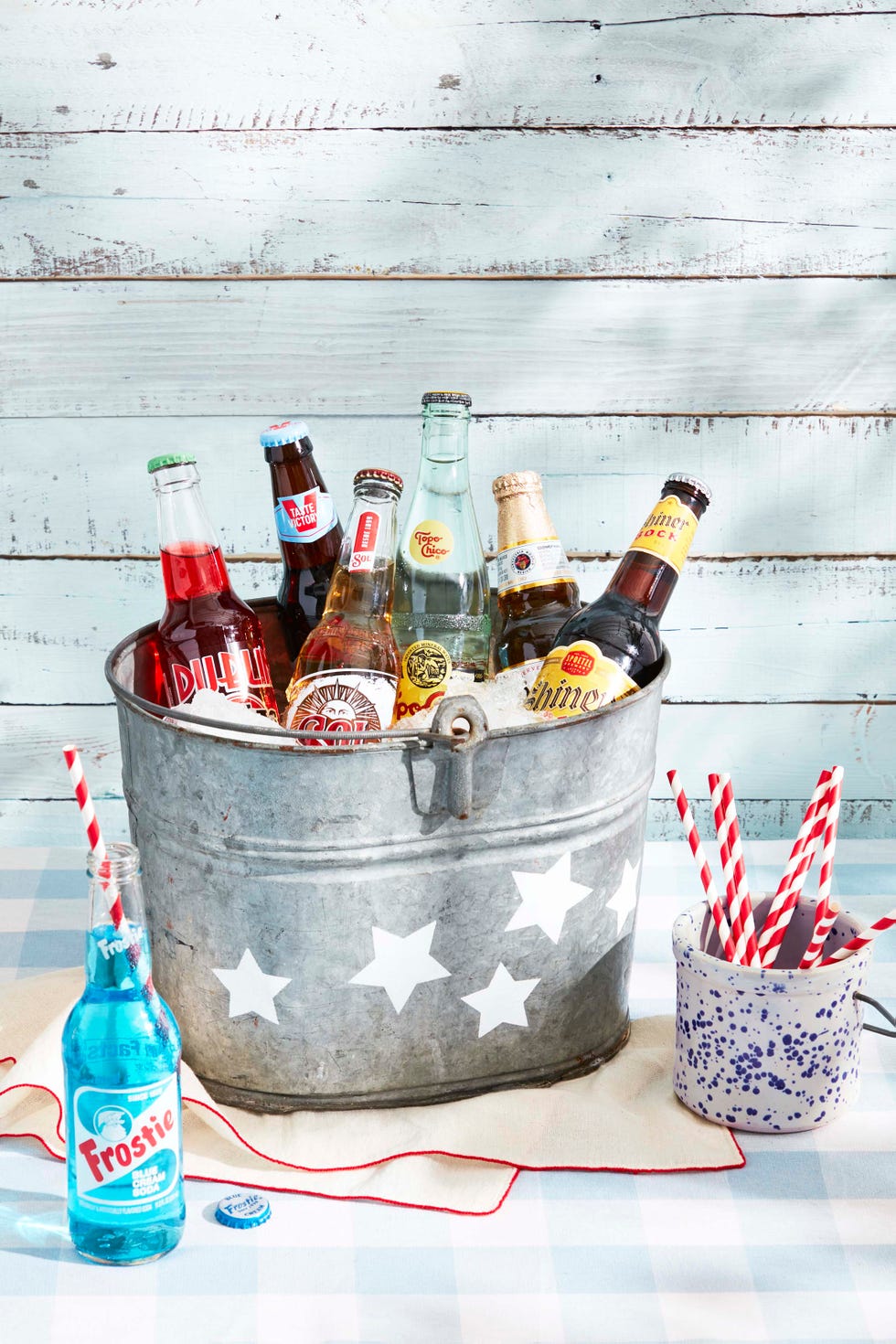 vintage galvanized metal bucket with white stars painted on it for 4th of july, filled with ice, beers and sodas