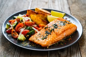 fried salmon steaks, fried potatoes and fresh vegetables on wooden table, best foods for muscle recovery