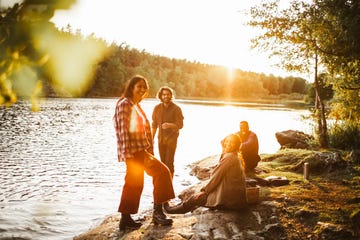 friends sitting on rock bank of a river during autumn