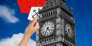 a hand holding a sign in front of a clock tower