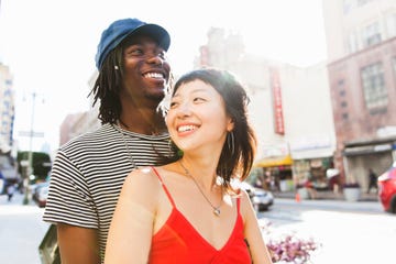 a happy young couple from the chest up smiling with a city street in the background