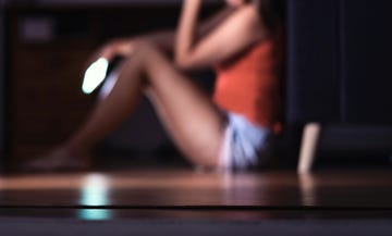 sad teenager with smartphone in her room sitting on floor lonely teen girl crying with mobile phone harassment or online cyber bullying in social media or internet mean message or troll comment