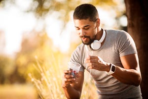 healthy foods to lose weight sporty young man eating berries from a plastic cup in a city park