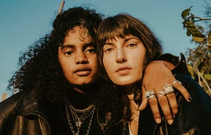 portrait of female friends with arm around outdoors on sunny day