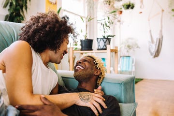 cheerful young gay couple being romantic indoors two romantic young male lovers smiling at each other while lying on the couch in their living room happy young gay couple bonding at home