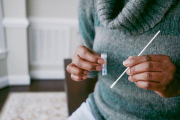 close up of unrecognizable black woman holding nasal swab and vial filled with reagent solution in preparation for at home covid test