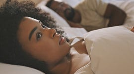 worried female laying in bed with her husband looking anxious and concerned while thinking of her relationship issues a man sleeping while his wife lays awake at night feeling depressed and troubled