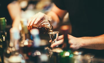 a few hands pouring liquid into a glass