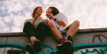 girlfriends eating ice cream while sitting in city during summer