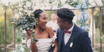 couple, flower confetti and outdoor wedding with event, walk and happy laugh in nature black woman, man and excited for marriage, floral bouquet or holding hands in park, party or together in aisle