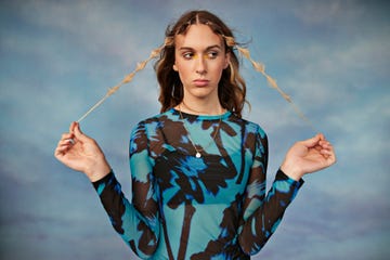 female transgender holding hair against colored background