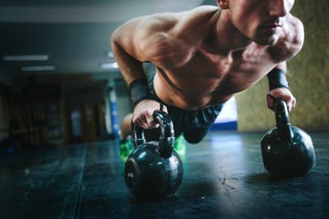 Young man doing pushups with kettle bells at the gym