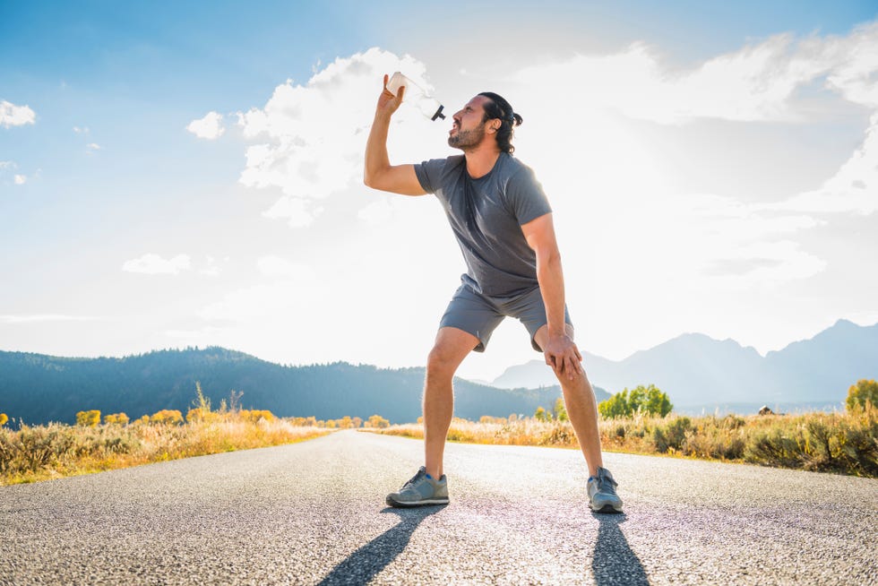 dude chugging h20 on an empty stretch of street by the mountains