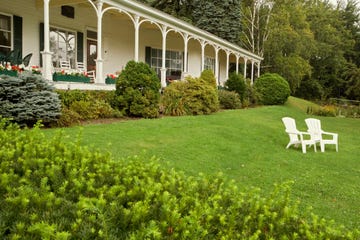 a lawn with white chairs and a white house with columns