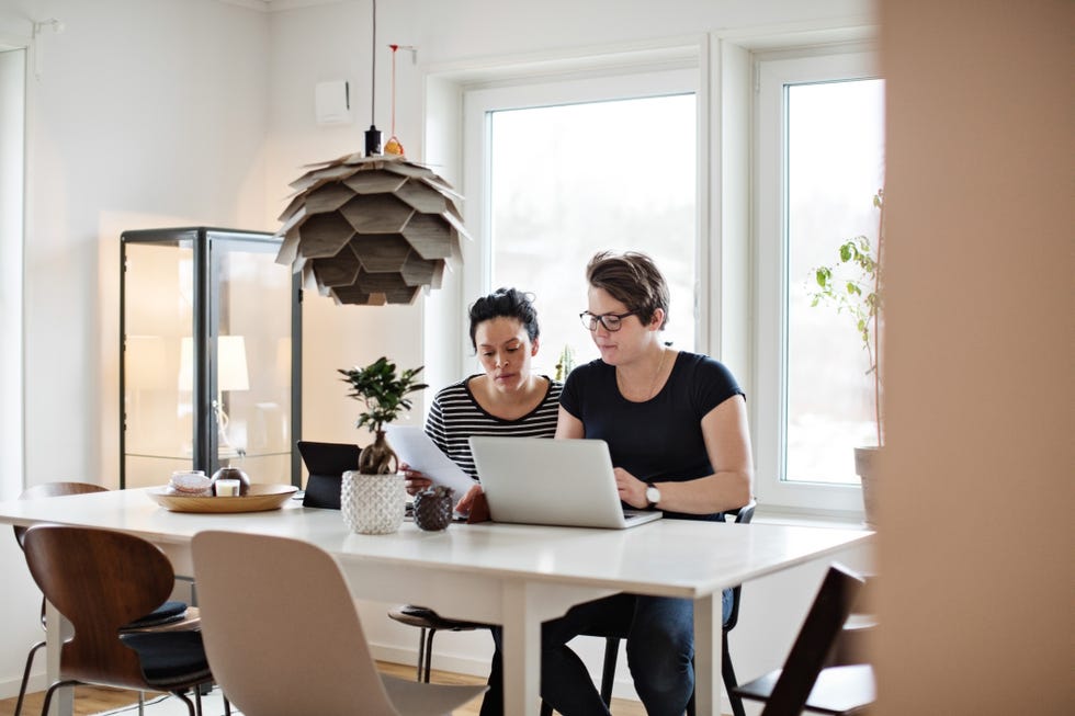 lesbian couple discussing financial bills over laptop while sitting at table