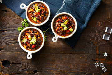 three bowls of hearty fall soup with avocado, beans, and carrots