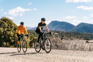 two people riding bikes on a gravel road