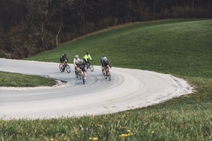 group of cyclist cycling up the hill on a curvy road