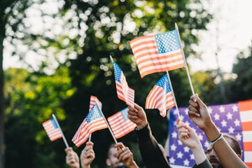 a group of people is waving small american flags at sunset