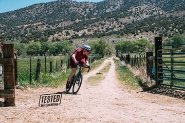 a person riding a bike on a dirt road in front of a mountain