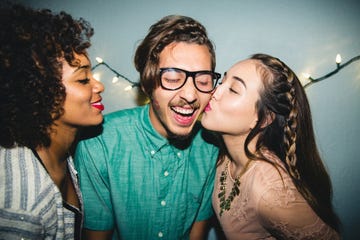 happy man enjoying kiss on cheek from female friend at home during party