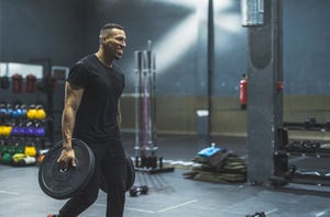 hispanic strong man in gym picking up weights