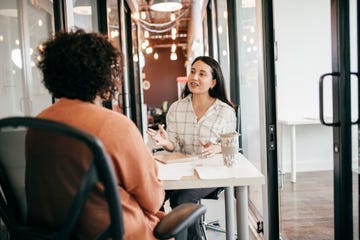 two women sat at a desk and talking in the office