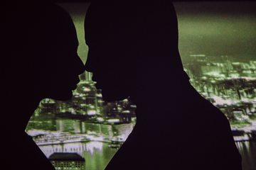 a shadowy couple kissing with a nighttime cityscape in the background