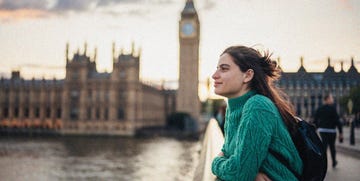 a woman leaning against a bridge with big ben visible in the background