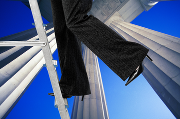 a person wearing a black jacket and black pants standing on a metal pole