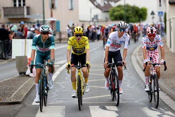 four cyclists riding side by side wearing the leaders jerseys in the tour de france