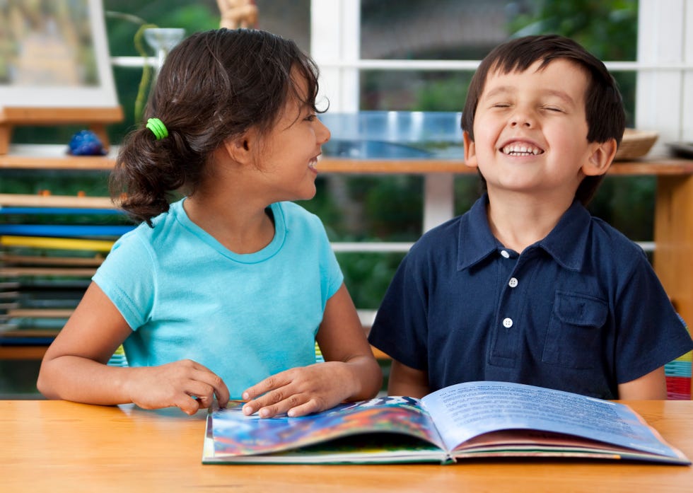 two laughing kids enjoying a book at school