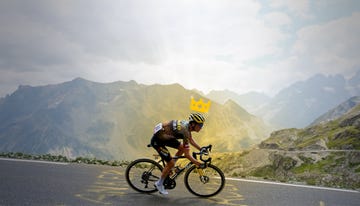 a man riding a bicycle on a road with mountains in the background