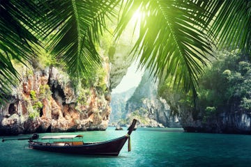 a long boat docked on beach in krabi, thailand summers