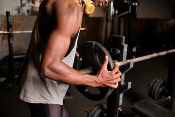 male athlete putting plate on barbell at gym