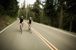 man and woman bicycling though the forest