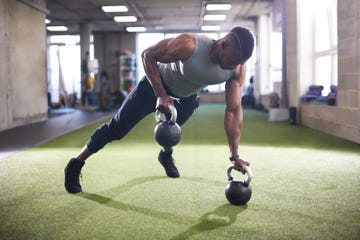 man doing plank with kettlebells in gym