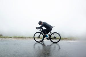 man relaxing on bicycle at wet street in foggy weather