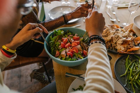 man serving salad from bowl during dinner party